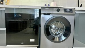 Una unidad compacta de lavadora y secadora con pantalla digital, ubicada en una cocina moderna.