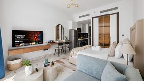 Een moderne woonkamer met een flatscreen televisie, een bank, een eethoek en een keuken.