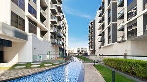 Een modern appartementencomplex met een zwembad, balkons en een verzorgd gazon.