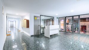 A modern reception area with a marble floor, a reception desk, and a glass door leading to a parking area. - Bright one-bedroom flat with excellent amenities (Madrid)