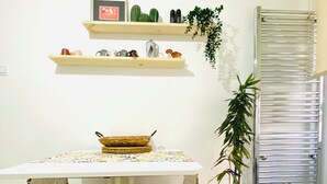 A kitchen with a table, stools, shelves with plants, and a radiator. - Aydinoglu Suites (Denizli)