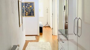 A hallway with a white radiator, a white rug, a coat rack, and a door leading to another room. - Aydinoglu Suites (Denizli)