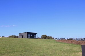 Ein modernes Gebäude auf einer grasbewachsen Anhöhe unter blauem Himmel.