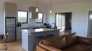 Una cucina moderna con isola centrale, elettrodomestici in acciaio inossidabile e illuminazione a sospensione.