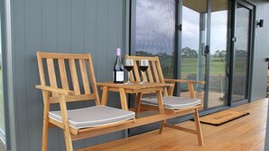 Un set di sedia e tavolo in legno su un pontile di legno, con una bottiglia di vino e due bicchieri.