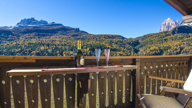Un molo in legno con vista sulle montagne e una bottiglia di vino.
