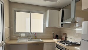 A modern kitchen with a double sink, stainless steel appliances, and a window providing natural light.