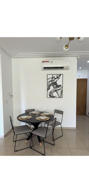 Zona pranzo con tavolo rotondo, quattro sedie e condizionatore d'aria a muro.