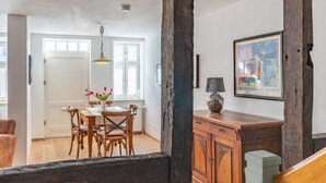 Un coin repas avec une table et des chaises en bois, un vase rempli de fleurs et une lampe posée sur un meuble en bois.