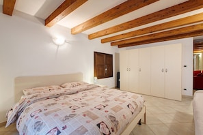 Un dormitorio con cama, armario y vigas de madera en el techo.