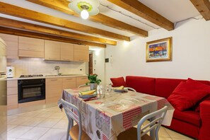 Una cocina con vigas de madera, una mesa de comedor con mantel y un sofá rojo.