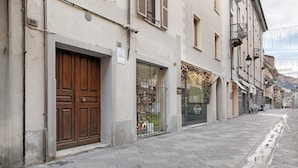 A street with buildings, a closed wooden door, and a shop with a glass front.