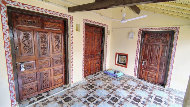 Un couloir doté de portes en bois richement décorées et d’un sol carrelé aux motifs élaborés.