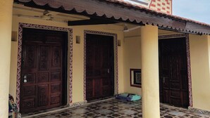 Un bâtiment doté de trois grandes portes en bois, d’un hall d’entrée carrelé et d’un toit à motifs rouges et blancs.