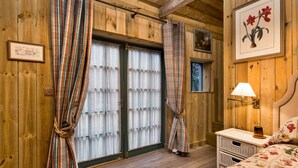 A wooden room with a bed, a nightstand, a lamp, and a window with curtains. - The Potting Shed at Island Hall (Godmanchester)