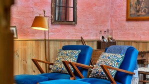 A room with two blue armchairs, a wooden floor, a pink wall, and a lamp. - The Potting Shed at Island Hall (Godmanchester)