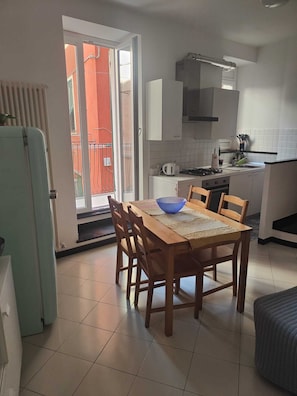 A compact kitchen with a dining table, chairs, and a refrigerator.