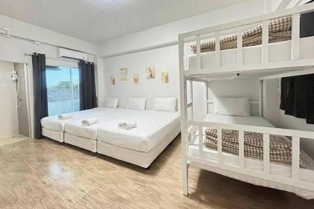 Quarto com uma cama de solteiro, uma beliche e uma janela com cortinas.