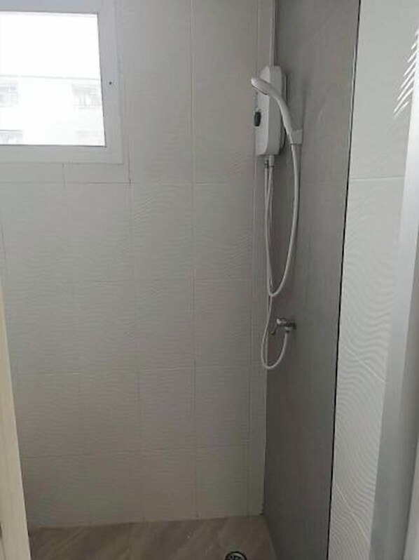 A small, enclosed shower area with a white showerhead and control panel, tiled walls, and a window. - Comfy Hotels Suvarnabhumi Airport (Bang Phli)