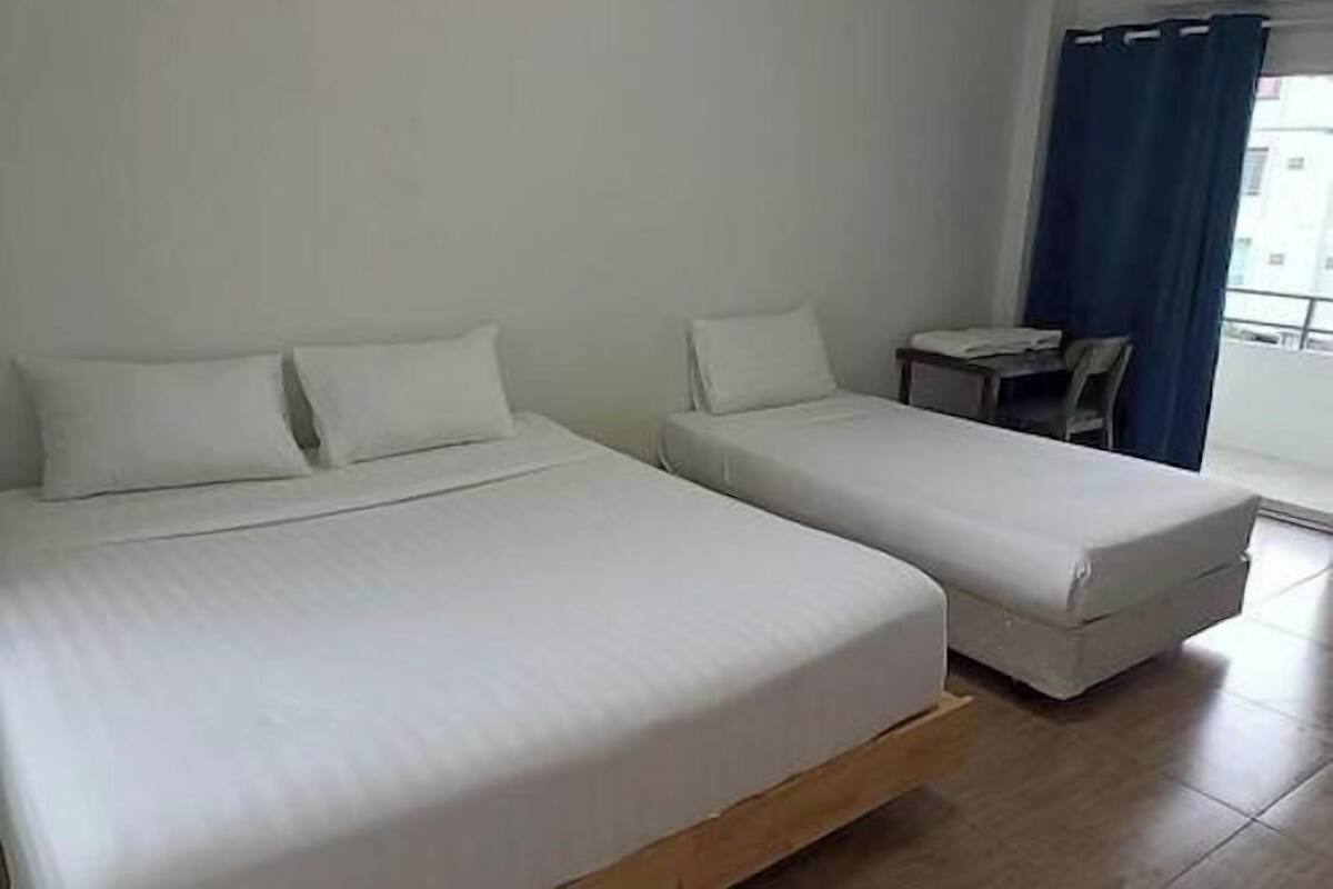 Quarto com duas camas de solteiro, uma mesa pequena e uma cadeira.
