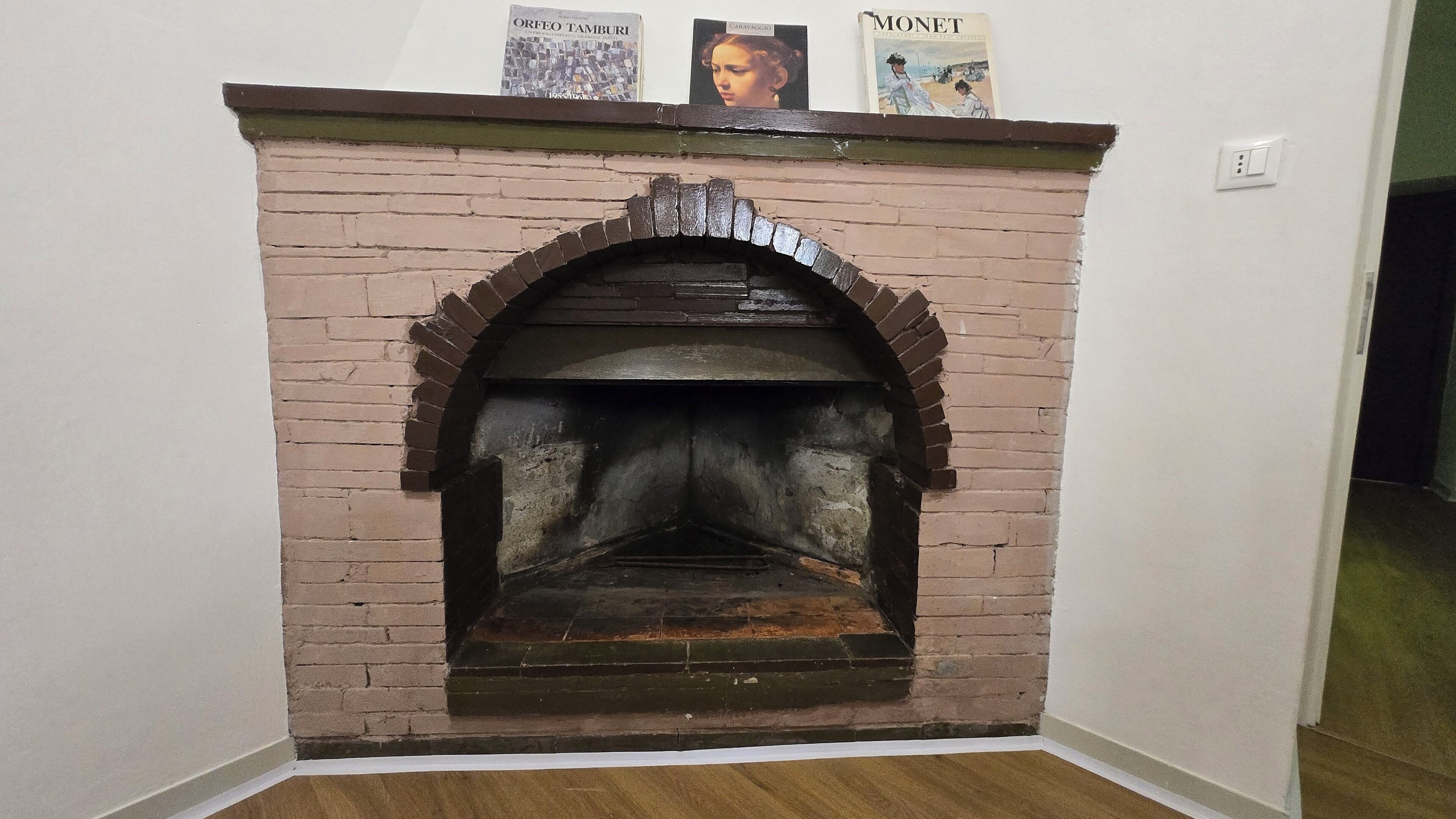 A brick fireplace with a mantel displaying books.