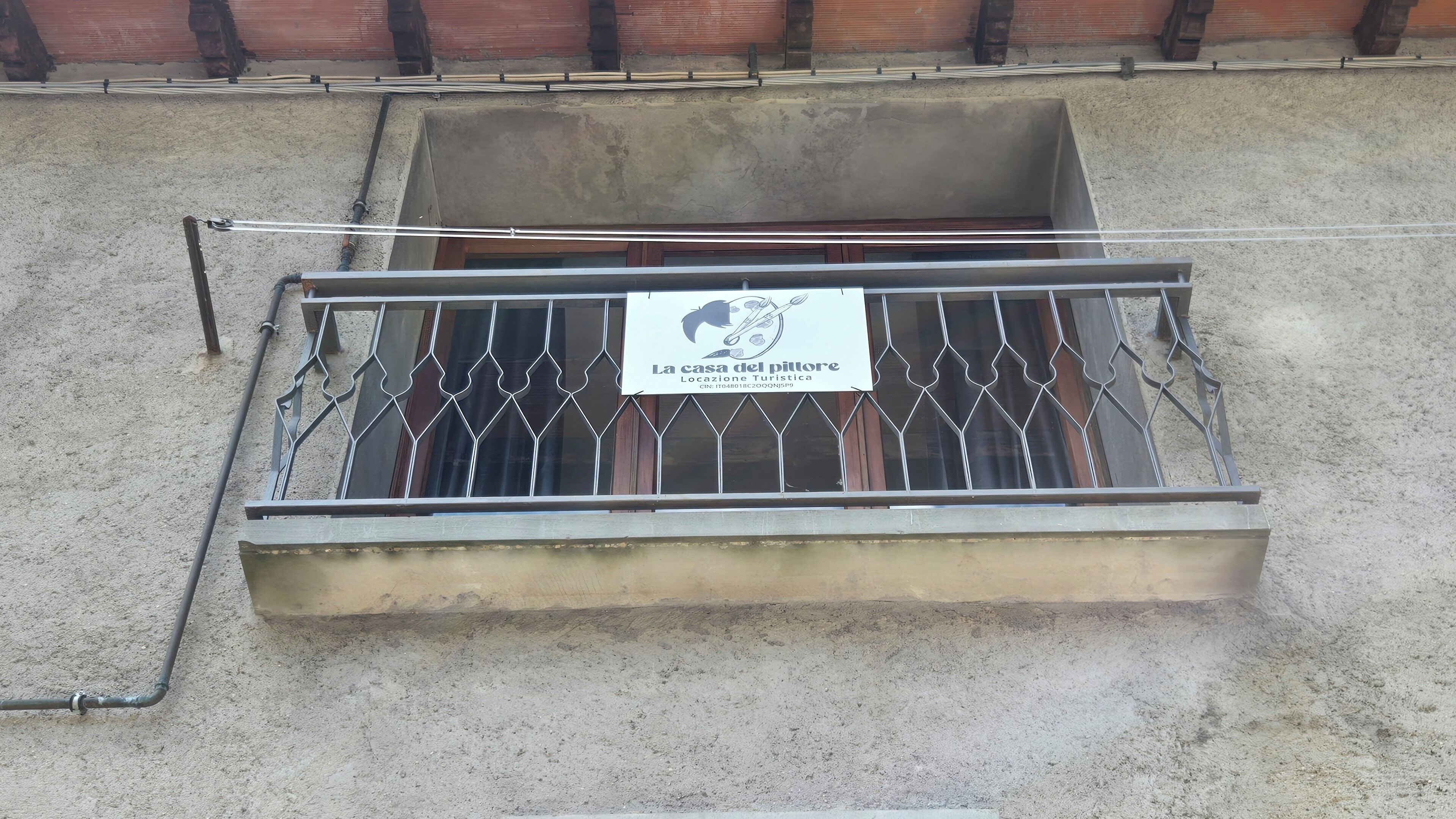 Een metalen balkon met een bord waarop staat: La casa del pittoresco Locazione Turistica.