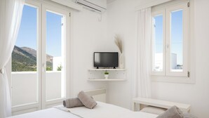 Ein Hotelzimmer mit Bett, Fernseher auf einem Regal, einem kleinen Tisch und Blick auf die Berge.