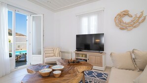 Ein modernes Wohnzimmer mit Couch, Fernseher, Holz-Couchtisch und einem gemusterten Teppich.