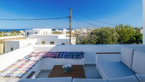 Eine Dachterrasse mit einem weißen Sofa, einem Holztisch und einer bunten Decke.