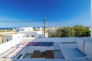 A rooftop terrace with a white sofa, a wooden table, and a colorful blanket. - Sunny villa with private pool and amazing views in Apollonia, Sifnos (Apollonia)