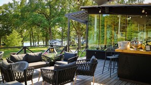 Een terras buiten met zitplaatsen, een bar en uitzicht op een meer.
