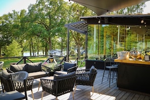 An outdoor deck with seating, a bar area, and a view of a lake. - Sånga Hotell & Konferens  (Svartsjo)