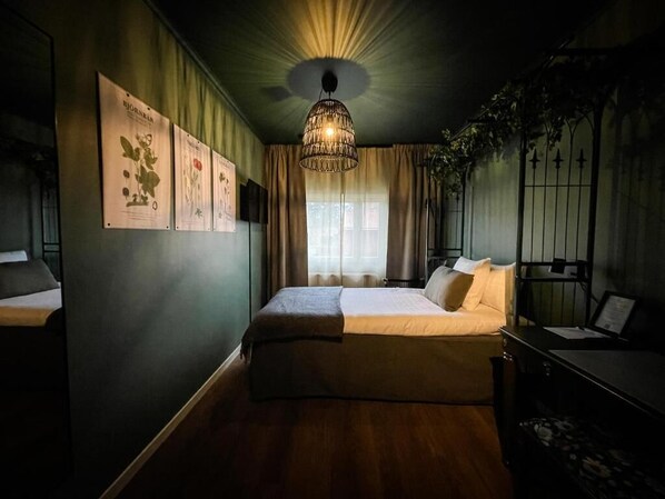 A bedroom with a large bed, a hanging light fixture, and a window with curtains.