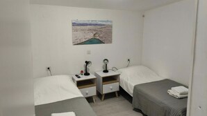 A small, clean room with two single beds, a bedside table with a lamp, a power outlet, and a wall-mounted picture of a landscape. - Tonino holiday house (Pag)