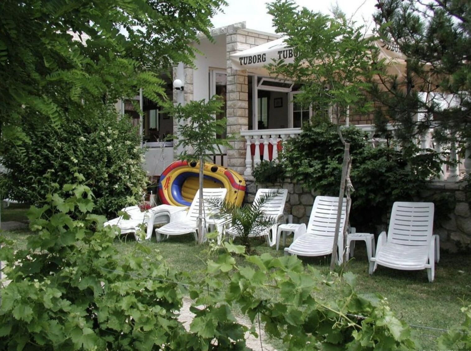 A garden area with white lounge chairs, a colorful inflatable slide, and a building with a sign reading "TUBORG TUB".