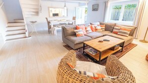 A spacious living area with a sofa set, a coffee table, and a dining table. - Charming farmhouse in the town center and within walking distance of the beaches (Larmor-Plage)