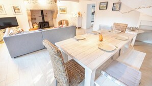 A modern living room with a sofa, a dining table set for four, and a fireplace. - Charming farmhouse in the town center and within walking distance of the beaches (Larmor-Plage)