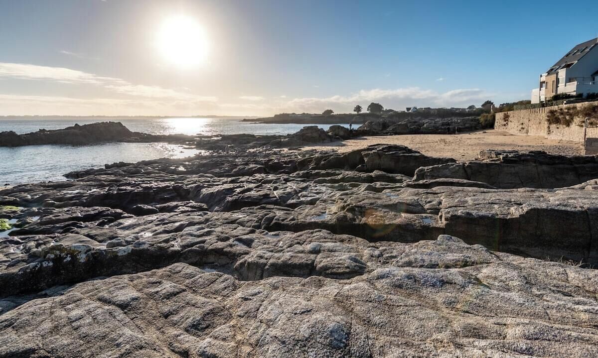 A rocky coastal landscape with a building on the right.