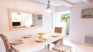 A dining area with a wooden table, wicker chairs, and cushioned benches. - Charming farmhouse in the town center and within walking distance of the beaches (Larmor-Plage)