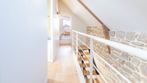 A narrow staircase with a stone wall on one side and a white railing. - Elegant Breton farmhouse 5 minutes from the ocean, beaches, and town center (Larmor-Plage)