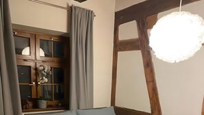 A bedroom with a bed, a window with curtains, a wooden ceiling, and a hanging light fixture. - Apartment 3 in the Heart of Ulm with Wi-Fi (Ulm)