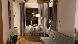 A cozy living room with a sofa, a dining table, and a TV. - Apartment 3 in the Heart of Ulm with Wi-Fi (Ulm)