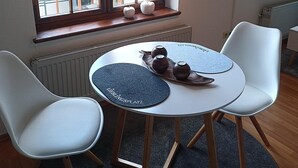 A dining area with a round table, two white chairs, a window with multiple panes, and a television mounted on the wall. - Apartment 6 Ulmer Spatz with Wi-Fi (Ulm)