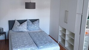 A bedroom with a bed, a wardrobe, and a hanging light fixture. - Apartment 6 Ulmer Spatz with Wi-Fi (Ulm)