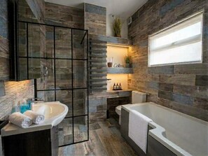 Ein modernes Badezimmer mit einer Glasdusche, einer freistehenden Badewanne und einem eingebauten Waschbecken.