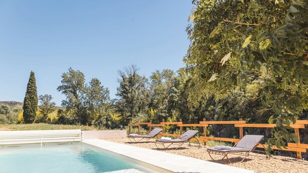 Ein Pool mit Liegestühlen und einem Holzzaun.