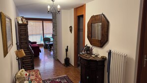 En gang med en trætrappe, en rød sofa, et træskab og et spejl på væggen.