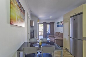 A compact living space with a dining area, a sofa, a refrigerator, and a painting on the wall. - Puerto Feliz 3: Beautiful renovated apartment with terrace and sea views (Puerto Rico)