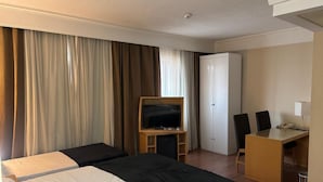 A hotel room with two beds, a TV, a desk with chairs, and a wardrobe. - Guarulhos Flats Services (Guarulhos)