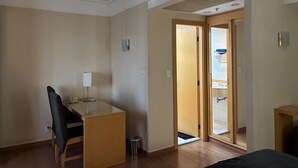 A hotel room with a desk, chair, and a door leading to a bathroom. - Guarulhos Flats Services (Guarulhos)